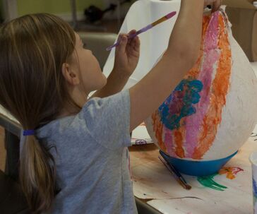 A color image of a child painting their paper maché hot air balloon that was made during the Hot Air Balloon Program. 